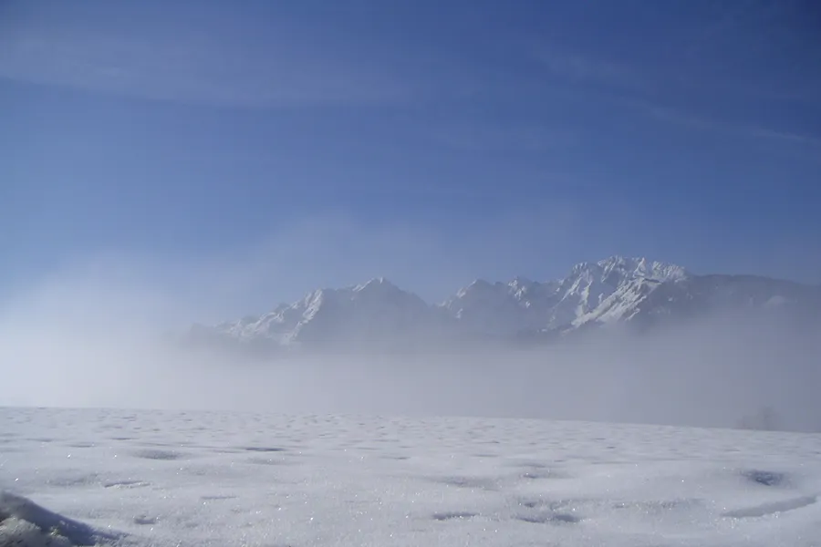 verschneite Wiese Sonne aufsteigender Dunst dahinter der hohe Göll